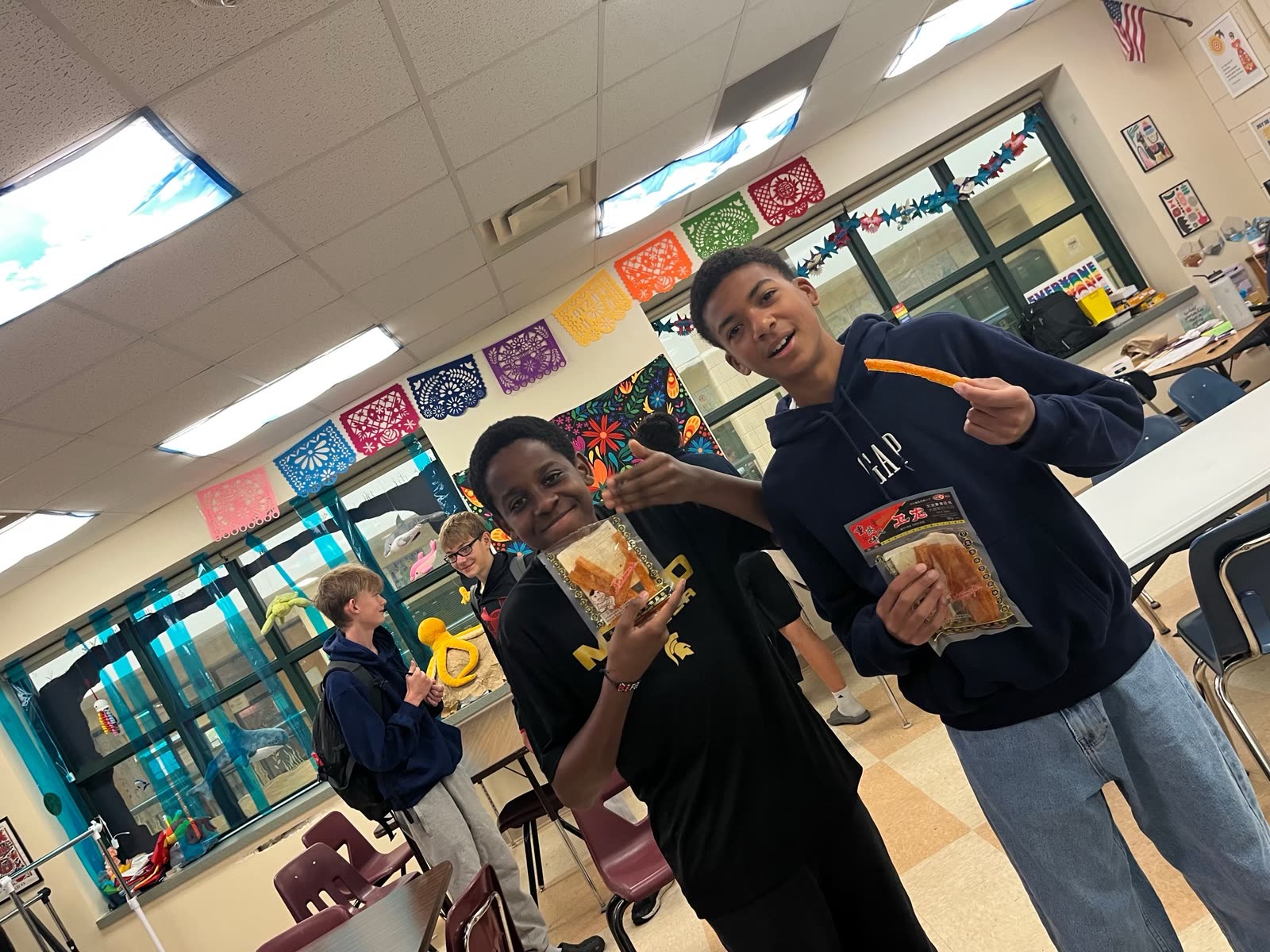 Two students holding up bags of spicy snacks